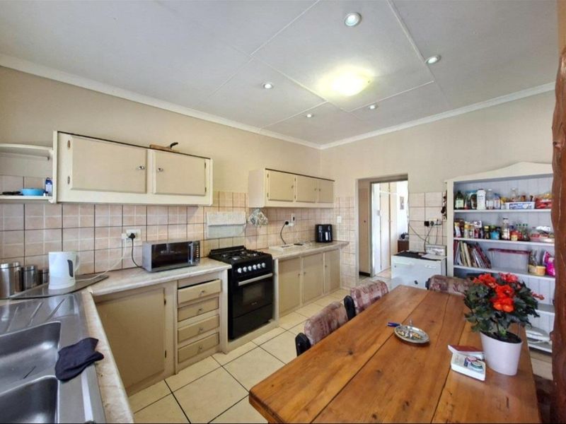 A functional kitchen featuring built-in cabinetry, a gas stove, tiled backsplash, and double sink, offering a practical layout with potential for modern updates.