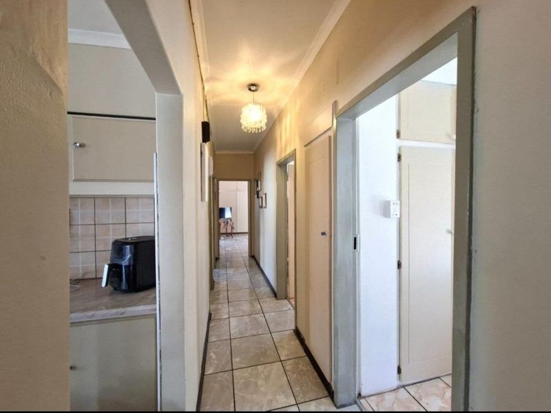 A functional hallway featuring tiled flooring, built-in storage cupboards, and access to adjacent rooms, including a view into the kitchen area.