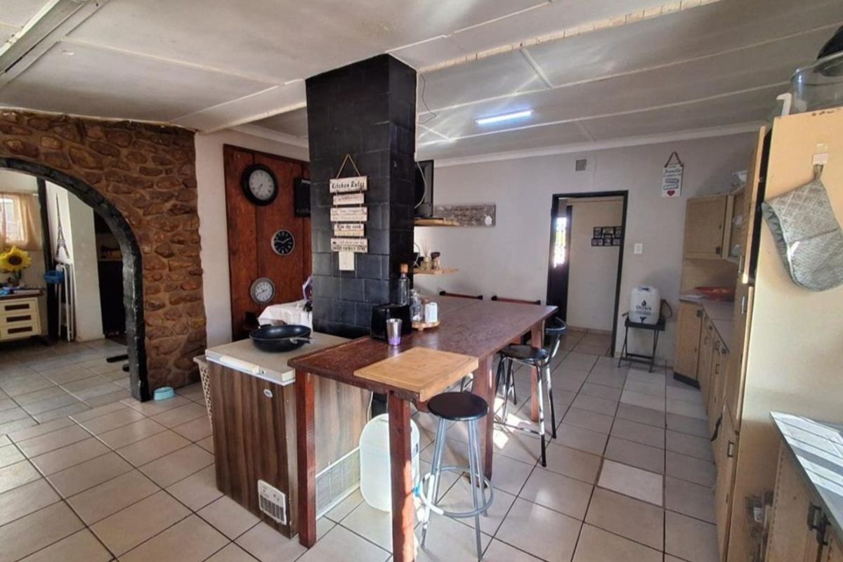 Kitchen area featuring a stone feature wall, central pillar, and tiled flooring, offering a rustic layout with potential for modern updates.