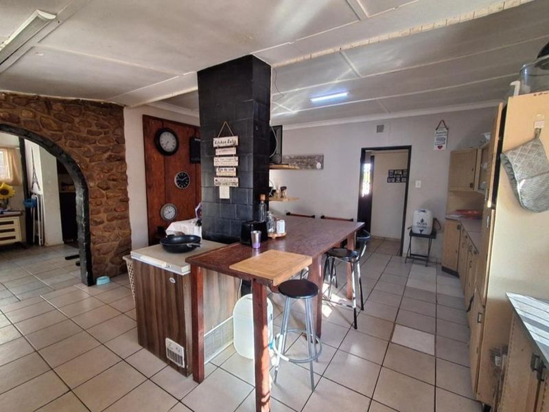 Kitchen area featuring a stone feature wall, central pillar, and tiled flooring, offering a rustic layout with potential for modern updates.