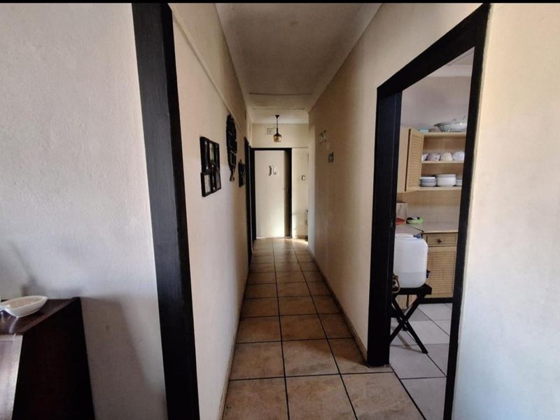 A central hallway with tiled flooring providing access to adjacent rooms, including a view into a kitchen area.