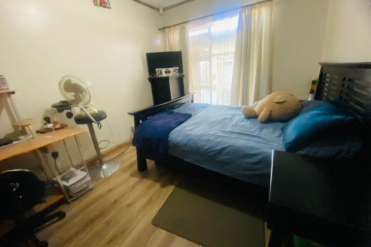A bedroom featuring laminate flooring and a sliding glass door providing natural light.