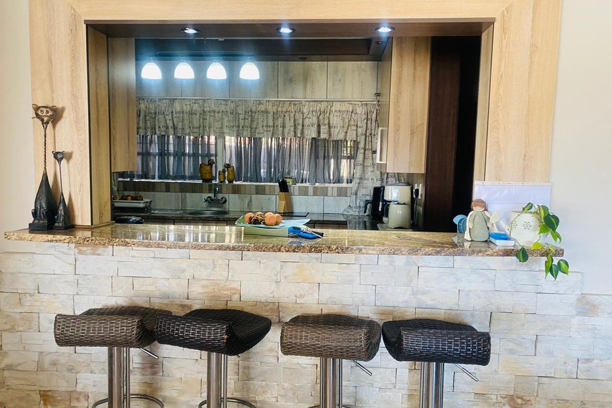 A kitchen view featuring a granite breakfast bar with stone veneer cladding and integrated cabinetry, providing a functional prep and dining space.