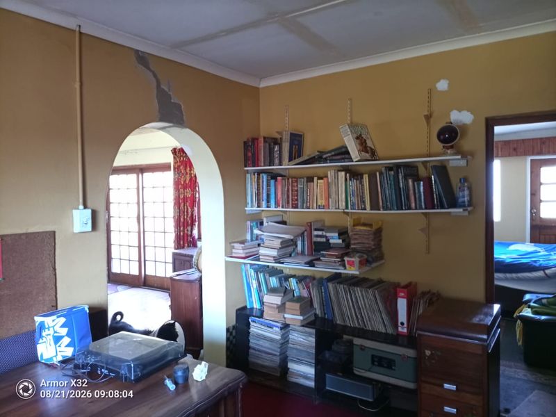 Living room area featuring an arched doorway, sliding glass doors, and visible wall damage requiring repair and cosmetic updates.