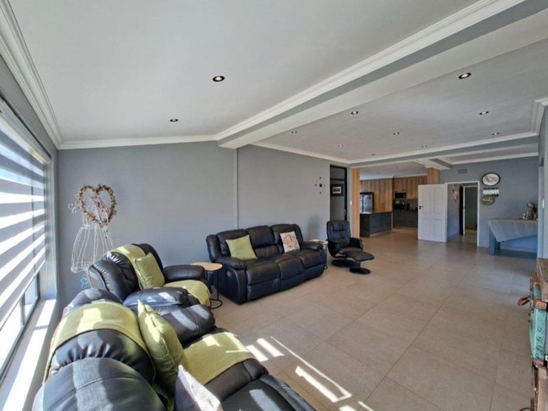 Spacious open-plan living area featuring tiled floors, recessed downlighting, and a seamless transition into the kitchen space.