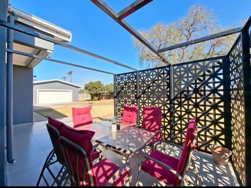 A covered outdoor patio area featuring a modern metal pergola structure and decorative laser-cut privacy screens, providing a shaded space for outdoor dining.