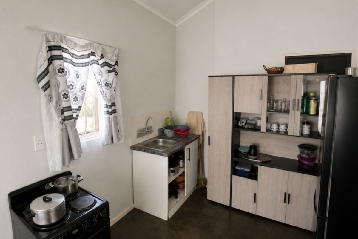 A compact kitchen area featuring a small sink, built-in cabinetry, and a freestanding stove, providing essential cooking and preparation space.