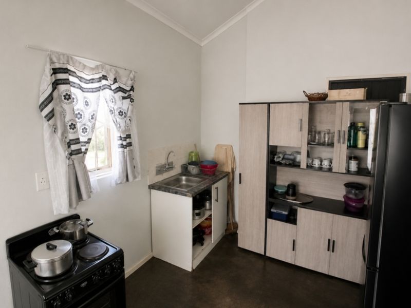 A compact kitchen area featuring a small sink, built-in cabinetry, and a freestanding stove, providing essential cooking and preparation space.