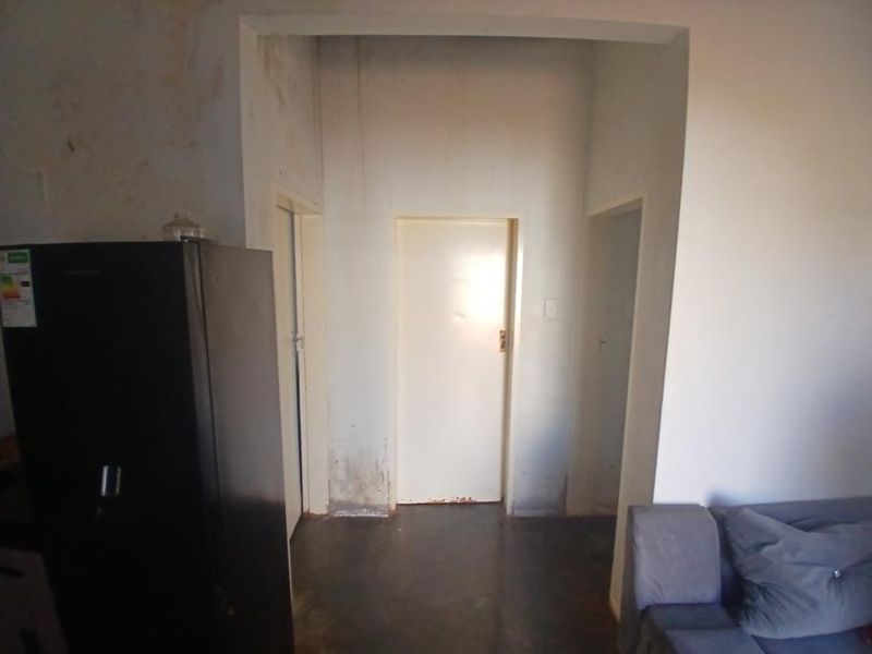 A narrow hallway featuring multiple internal doors, showing significant signs of wall staining and surface wear requiring maintenance and cosmetic repair.