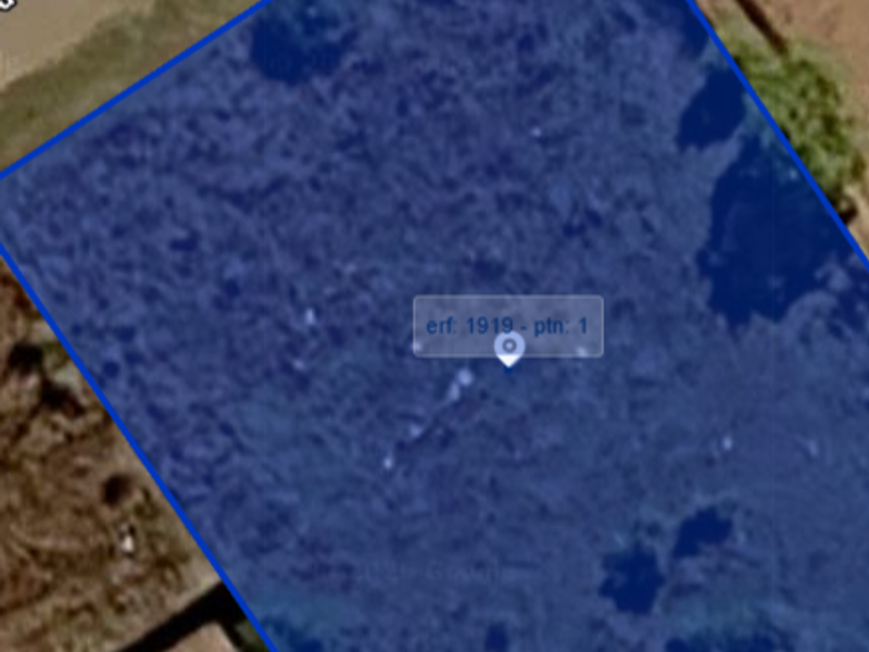 An aerial view of a vacant residential plot, highlighting the property boundaries and surrounding landscape.