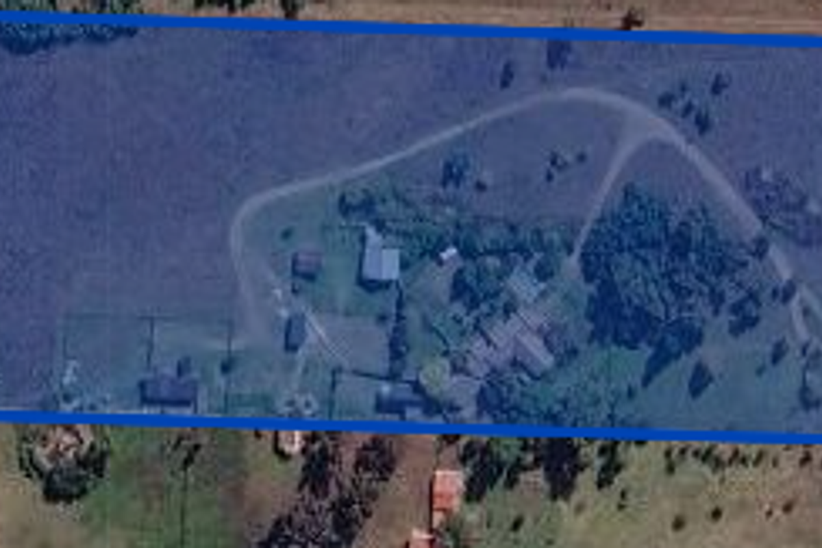 Aerial view of a large residential vacant land plot featuring existing outbuildings, internal driveway access, and established boundary fencing.