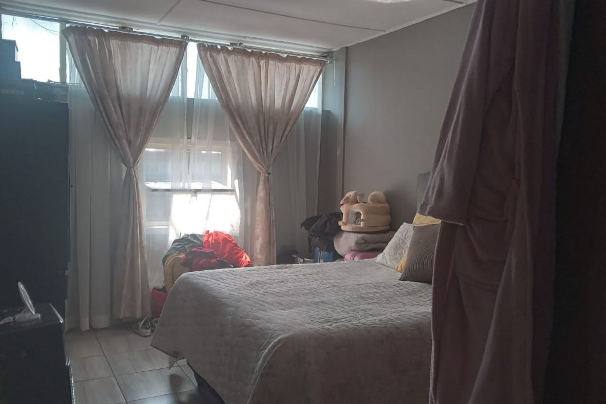 A bedroom featuring tiled flooring and a large window allowing natural light into the space.