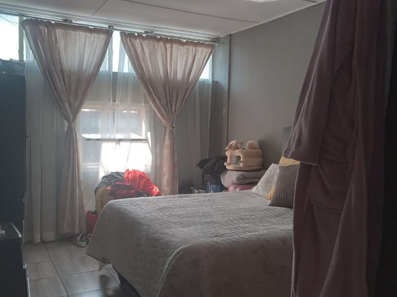 A bedroom featuring tiled flooring and a large window allowing natural light into the space.