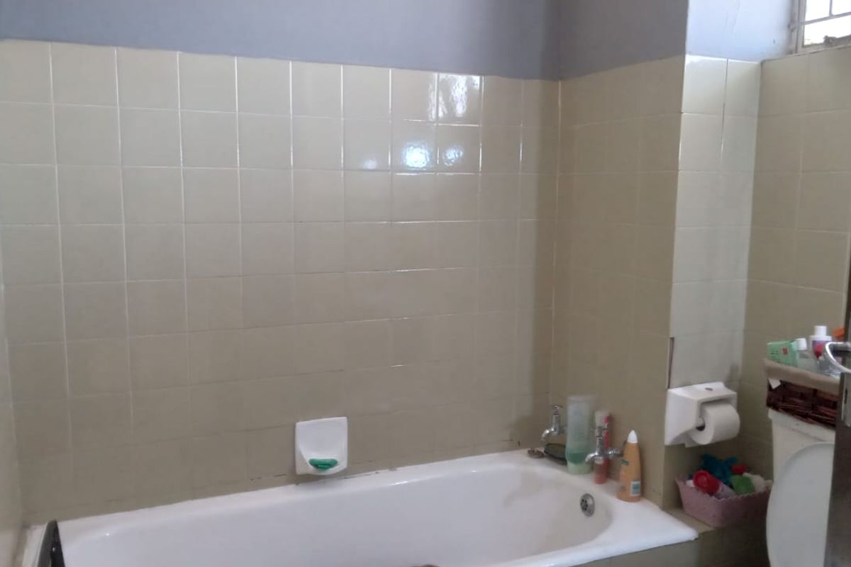 A functional bathroom featuring a standard bathtub, wall tiling, and a toilet, offering a dated aesthetic ready for modernization.