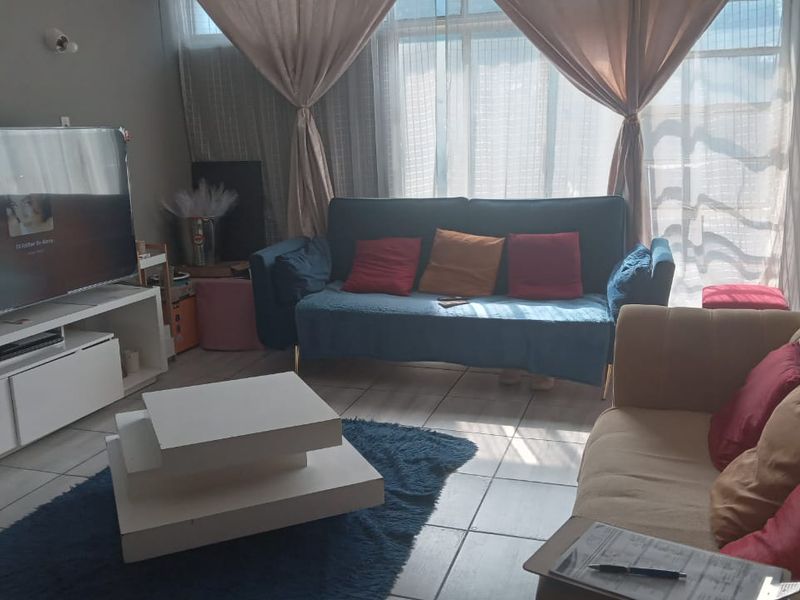 A comfortable living room featuring tiled flooring and a large window that allows for natural light.