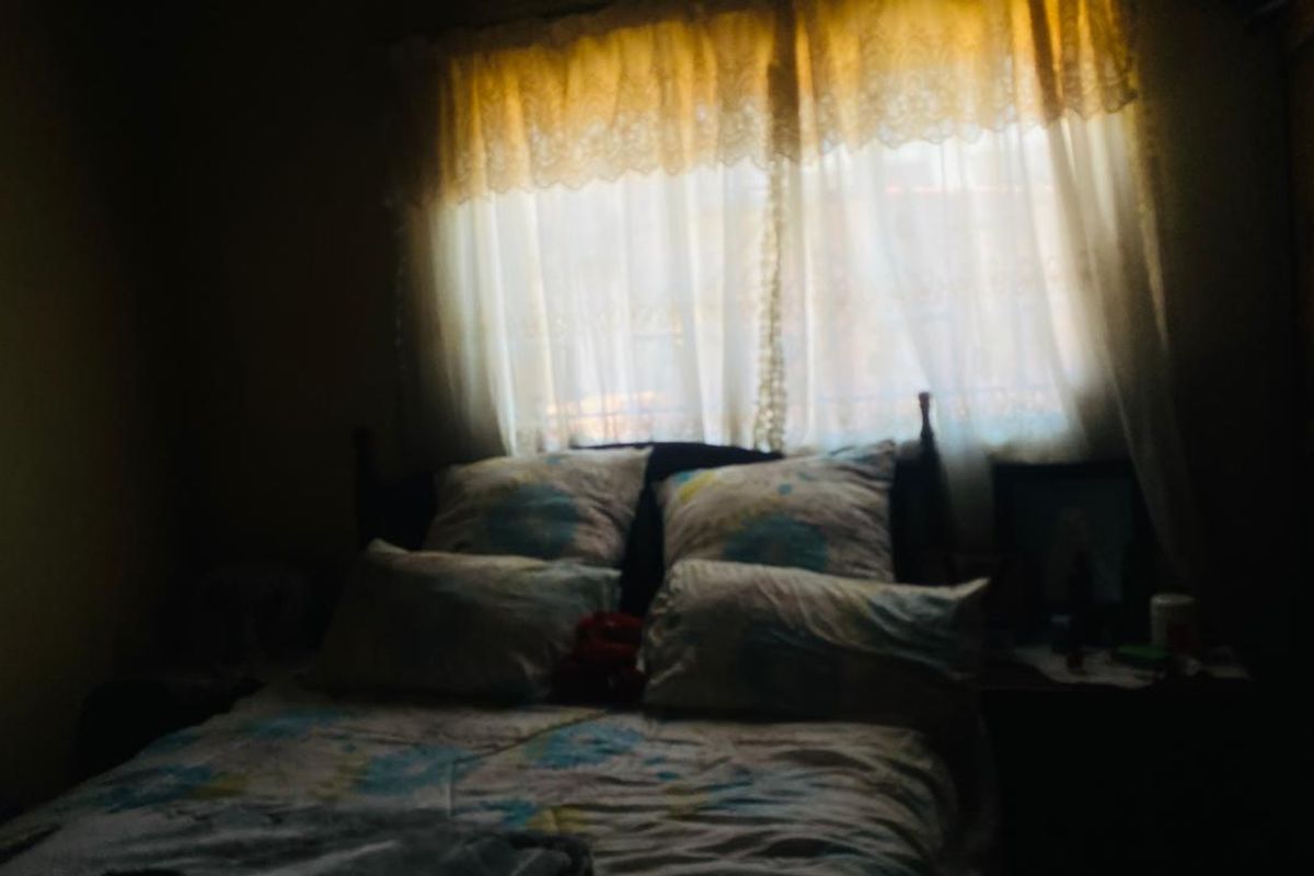 A dimly lit bedroom featuring a window with curtains, providing a private sleeping space.
