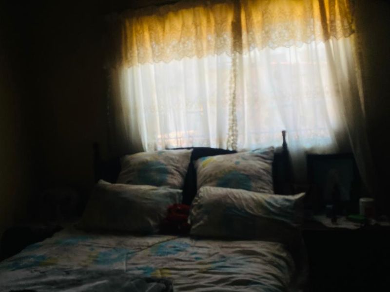 A dimly lit bedroom featuring a window with curtains, providing a private sleeping space.