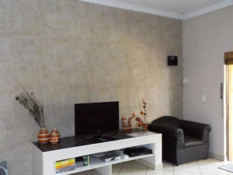 A living room area featuring a tiled accent wall, ceramic floor tiles, and coved ceiling cornicing.