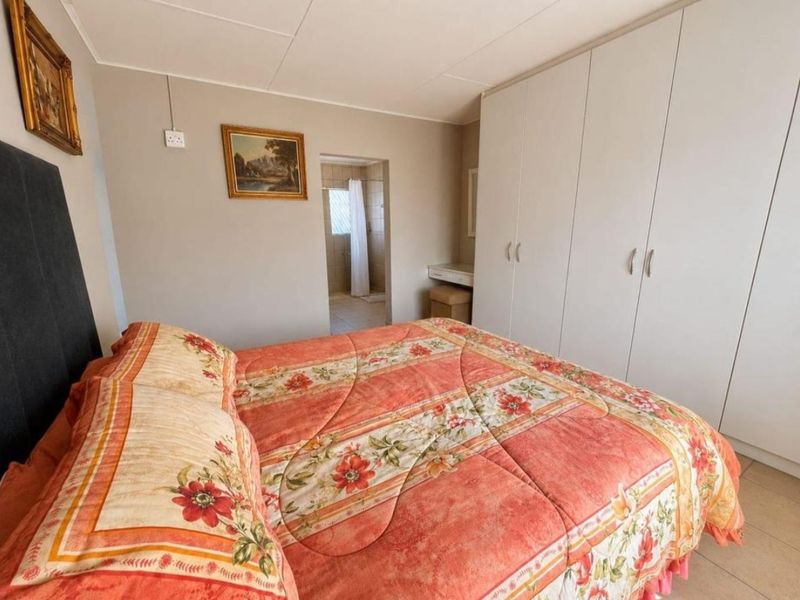 A bedroom featuring built-in cupboards and direct access to an en-suite bathroom with tiled flooring throughout.