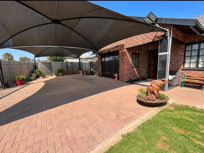 Rear exterior area featuring brick paving, a large shade sail structure, and a secure perimeter wall, providing a functional outdoor space.