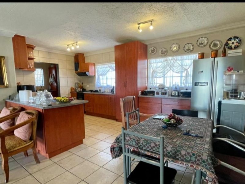 Open-plan kitchen and dining area featuring wooden cabinetry, a central island, and tiled flooring throughout.