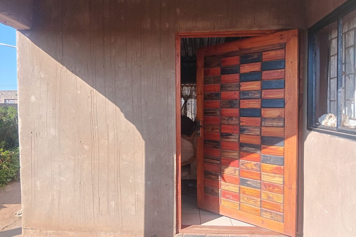 Entrance area featuring a decorative timber front door set within a plastered exterior wall.