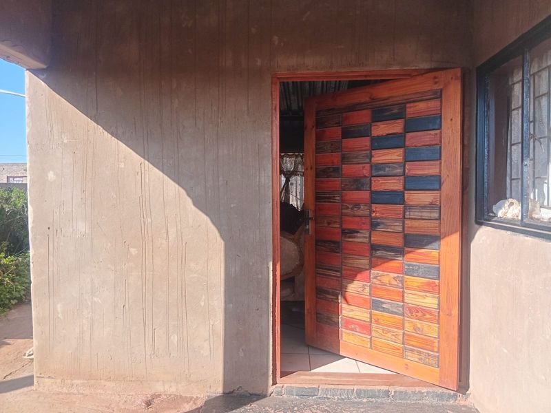 Entrance area featuring a decorative timber front door set within a plastered exterior wall.