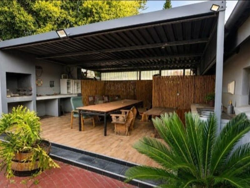 Covered outdoor patio area featuring a built-in braai, concrete prep surfaces, and tiled flooring, ideal for alfresco dining and entertaining.
