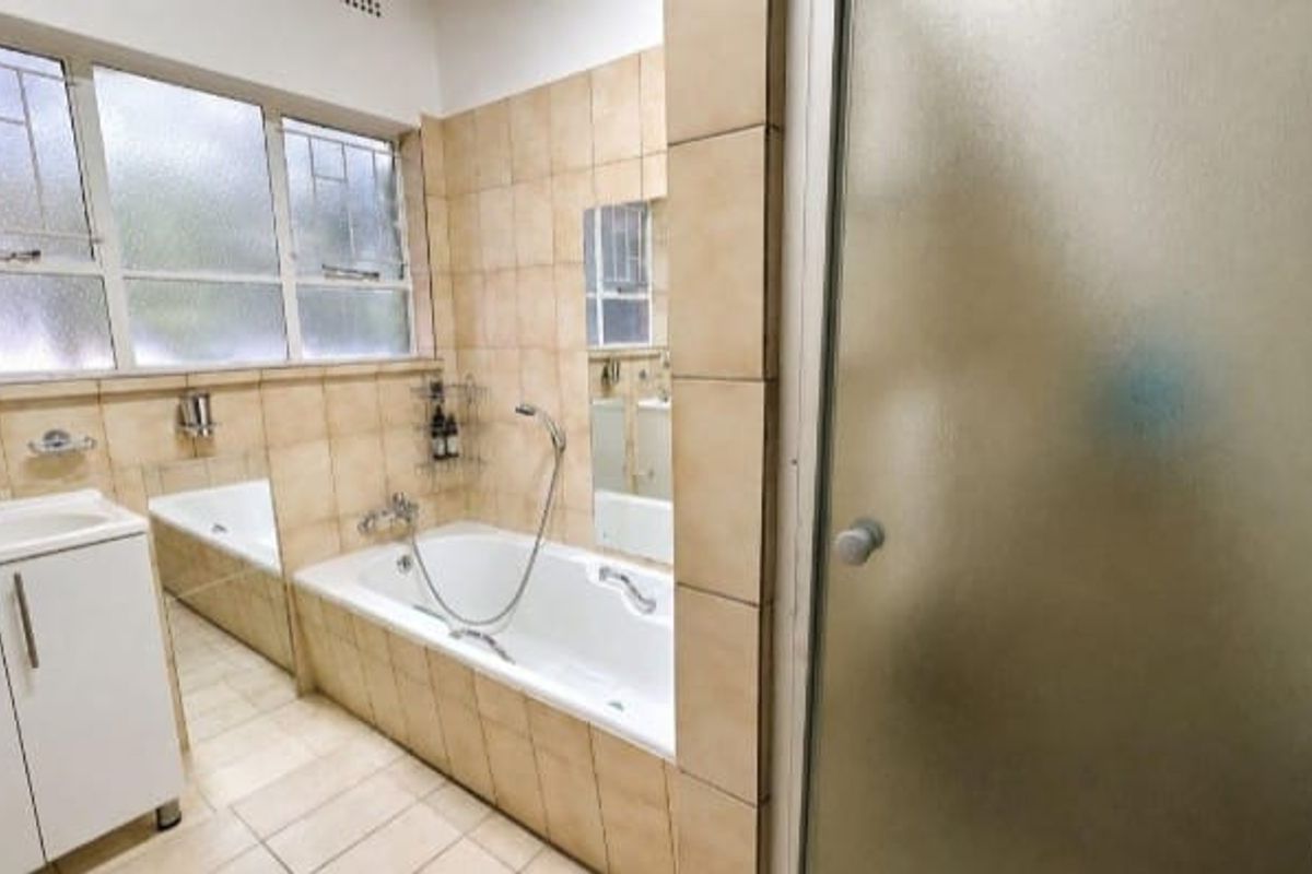 A functional bathroom featuring a built-in vanity, a bathtub, and a separate shower enclosure with tiled finishes throughout.
