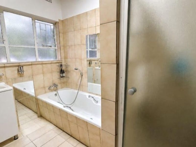 A functional bathroom featuring a built-in vanity, a bathtub, and a separate shower enclosure with tiled finishes throughout.