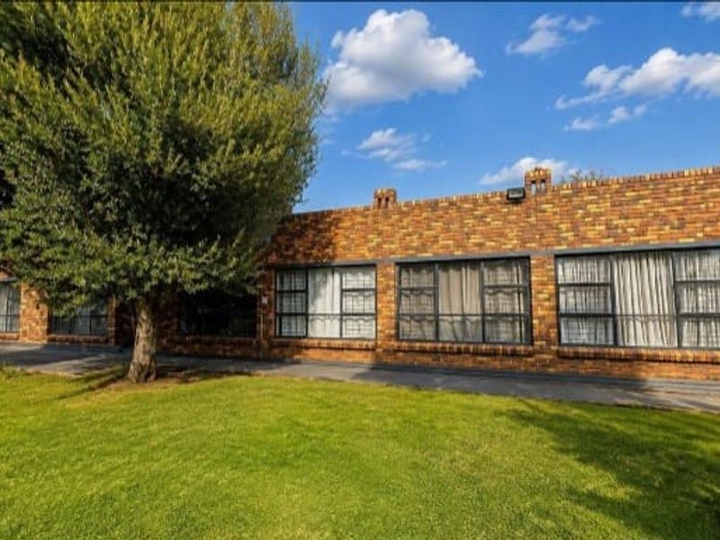 A well-maintained single-story face-brick home featuring large windows, a paved front walkway, and a neat, established lawn.