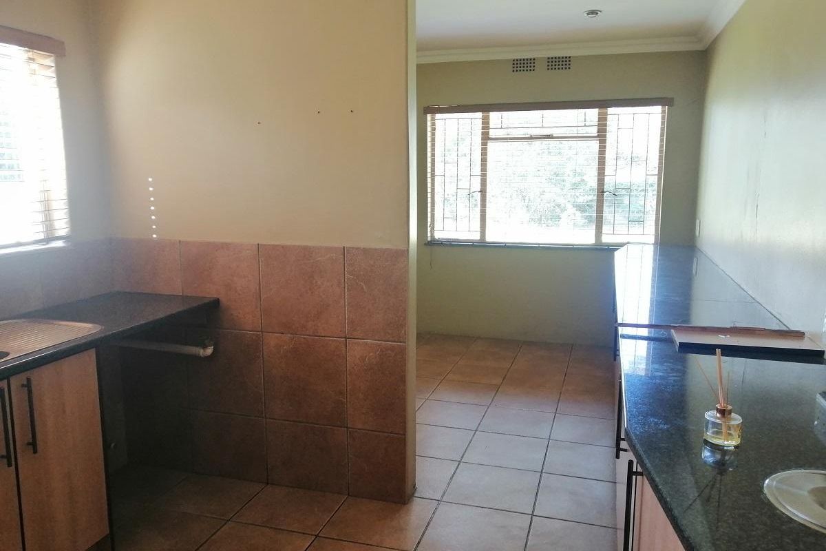 A functional kitchen area featuring granite countertops, tiled splashbacks, and tiled flooring, offering a practical layout with ample workspace.