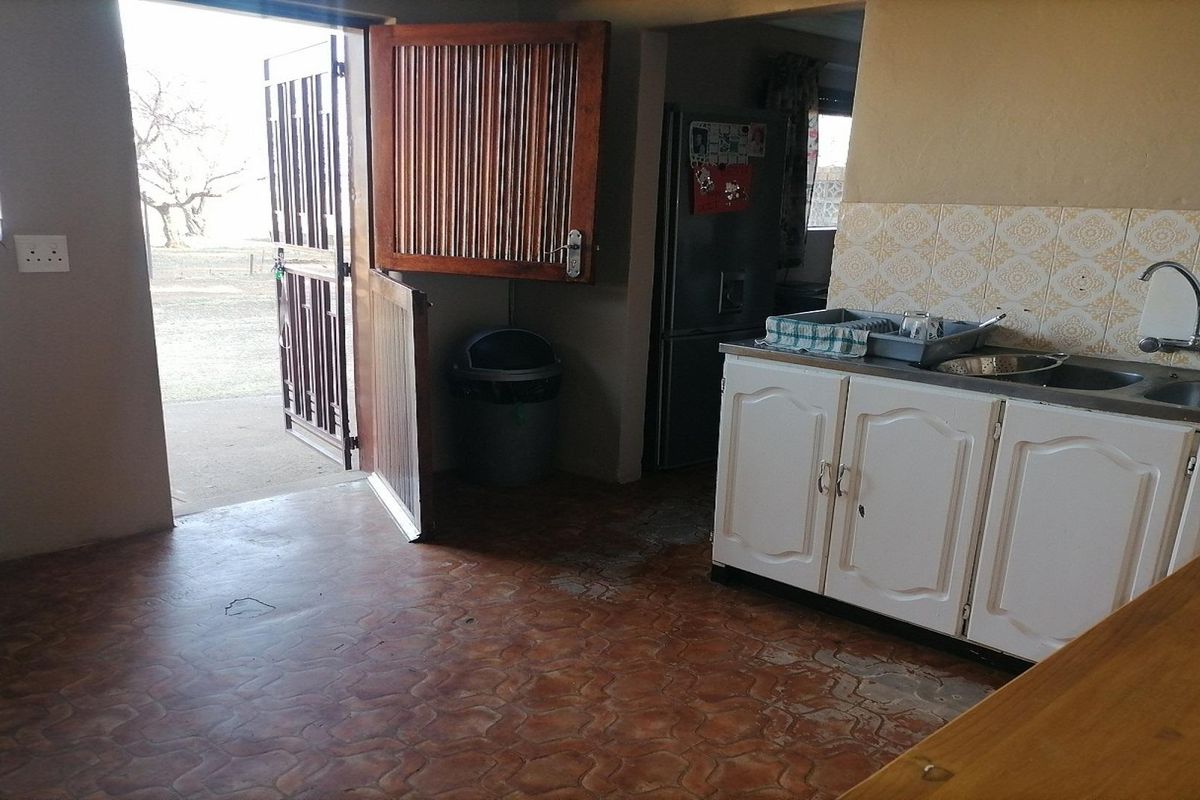 A functional kitchen area featuring built-in cabinetry, a double sink, and direct access to the exterior through a stable-style door.