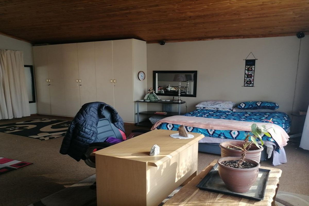 Spacious bedroom featuring built-in cupboards, a timber-clad ceiling, and large windows allowing for natural light.