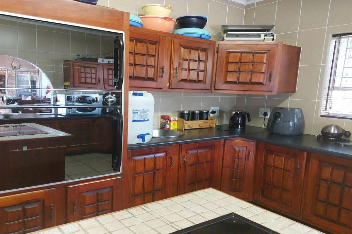 A functional kitchen featuring traditional wooden cabinetry, tiled splashbacks, and a tiled countertop, offering ample storage and workspace.