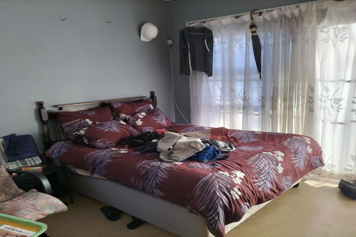 A bedroom featuring a large window with sheer curtains, providing natural light and access to the exterior.