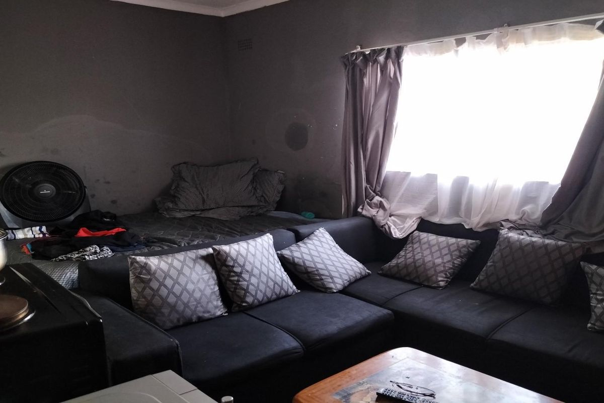 A living room space featuring dark walls and a window with curtains, requiring cosmetic updates to improve the overall aesthetic and condition.