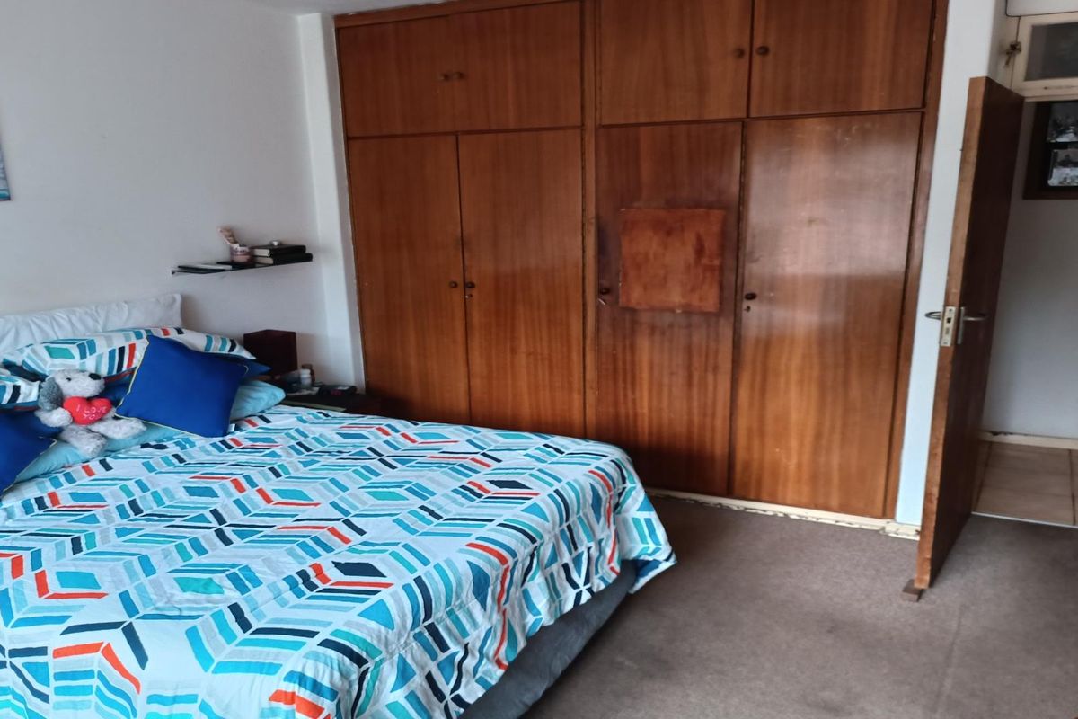 A bedroom featuring built-in wooden cupboards with overhead storage and carpeted flooring, providing functional storage space within the apartment.