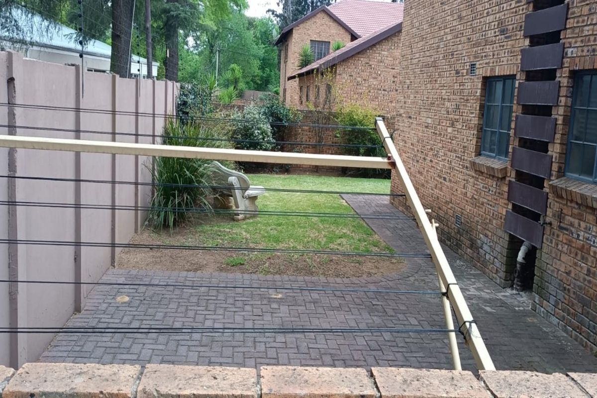 A private rear garden area featuring a paved patio, a small lawn, and a brick townhouse exterior wall.