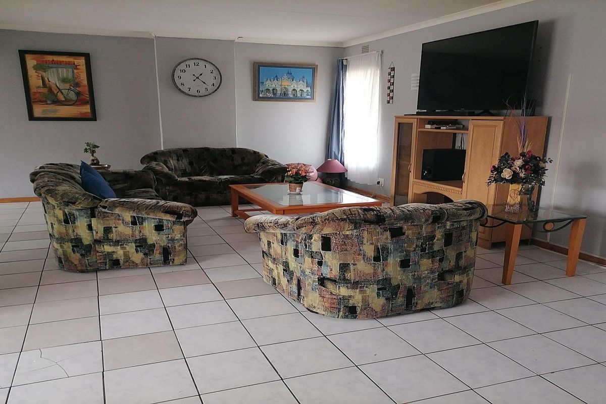 A spacious living room featuring neutral wall tones and large format floor tiles, providing a functional and open layout for relaxation.