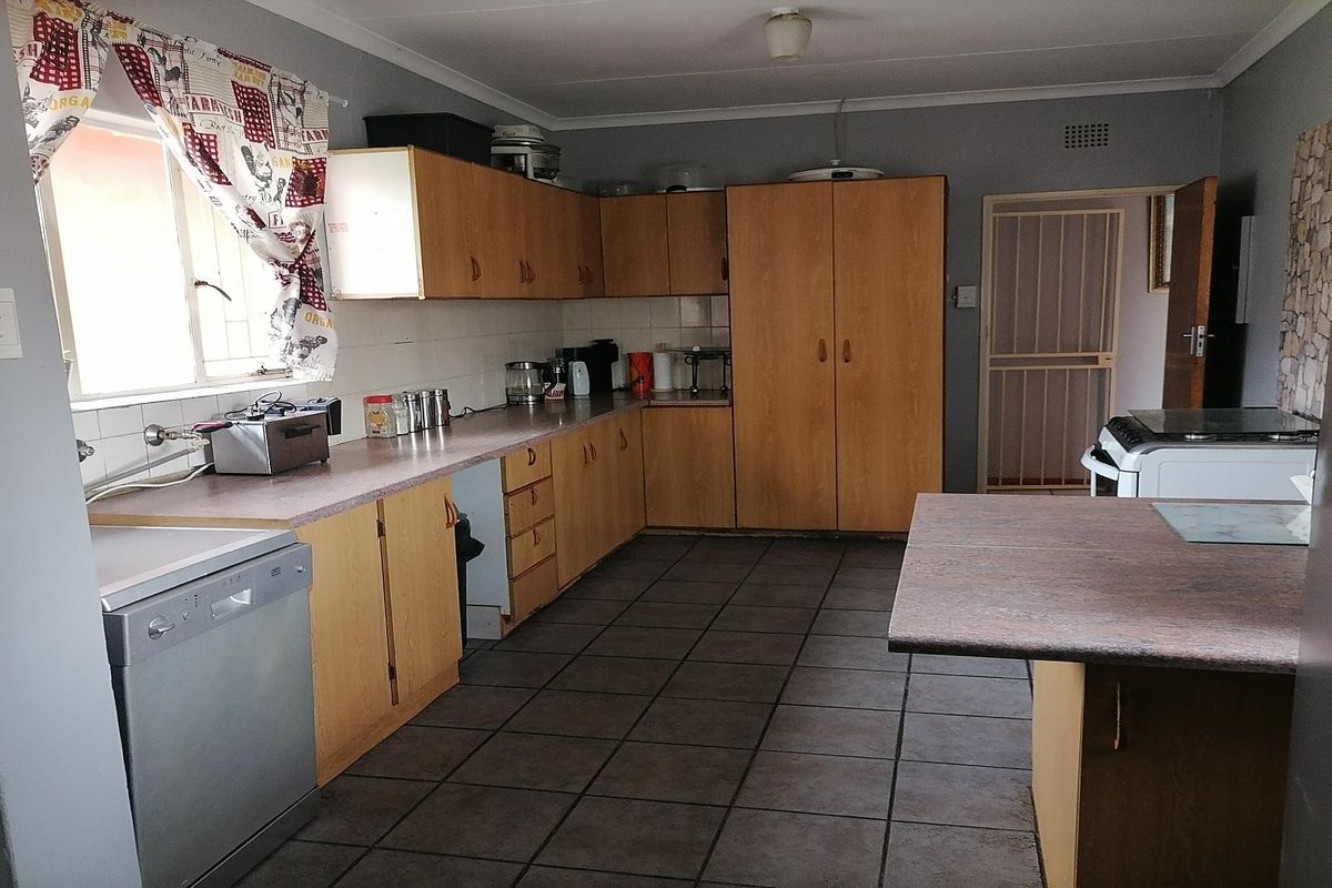 A functional kitchen featuring wood-finish cabinetry, laminate countertops, tiled flooring, and a breakfast bar, offering a practical layout for daily meal preparation.