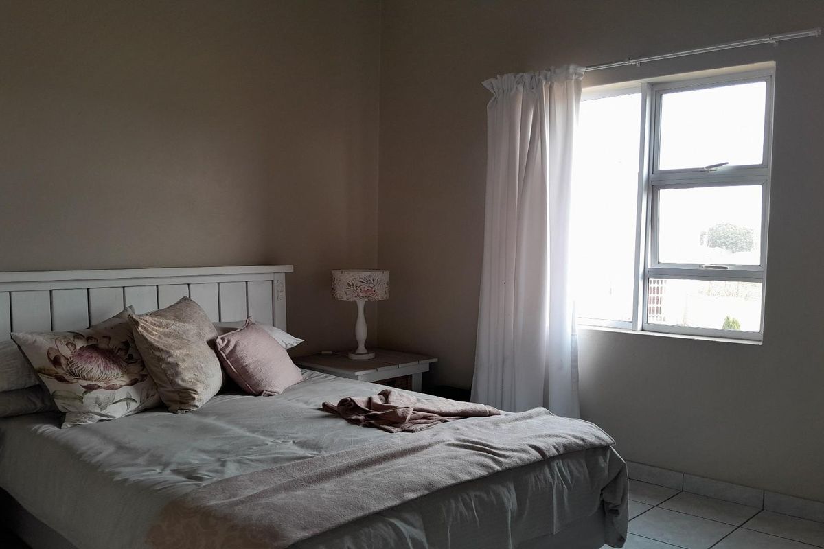 A bedroom featuring tiled flooring and a window with natural light, providing a neutral space for rest.