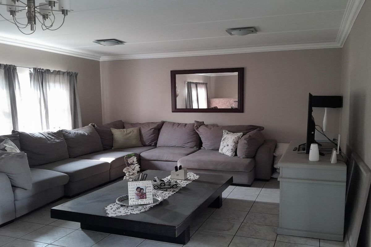 A comfortable living room featuring tiled flooring, crown molding, and a neutral color palette, providing a functional and inviting space for relaxation.