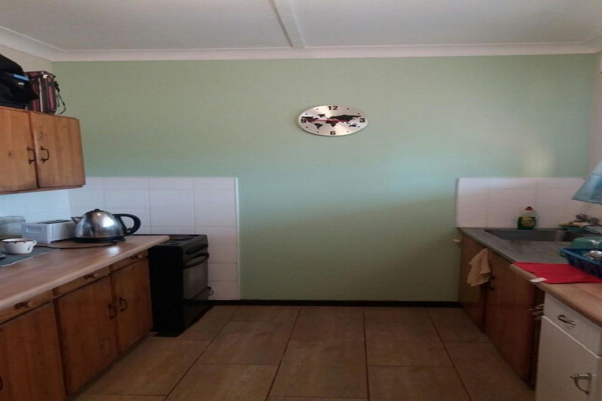 A functional kitchen featuring wooden cabinetry, tiled splashbacks, and tiled flooring, offering a practical layout for daily meal preparation.