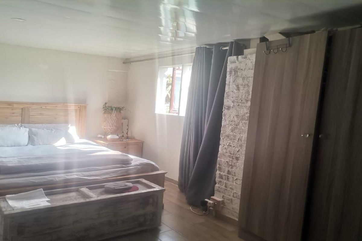 A bedroom featuring tiled flooring, a painted ceiling, and a section of exposed brickwork, providing a rustic aesthetic.