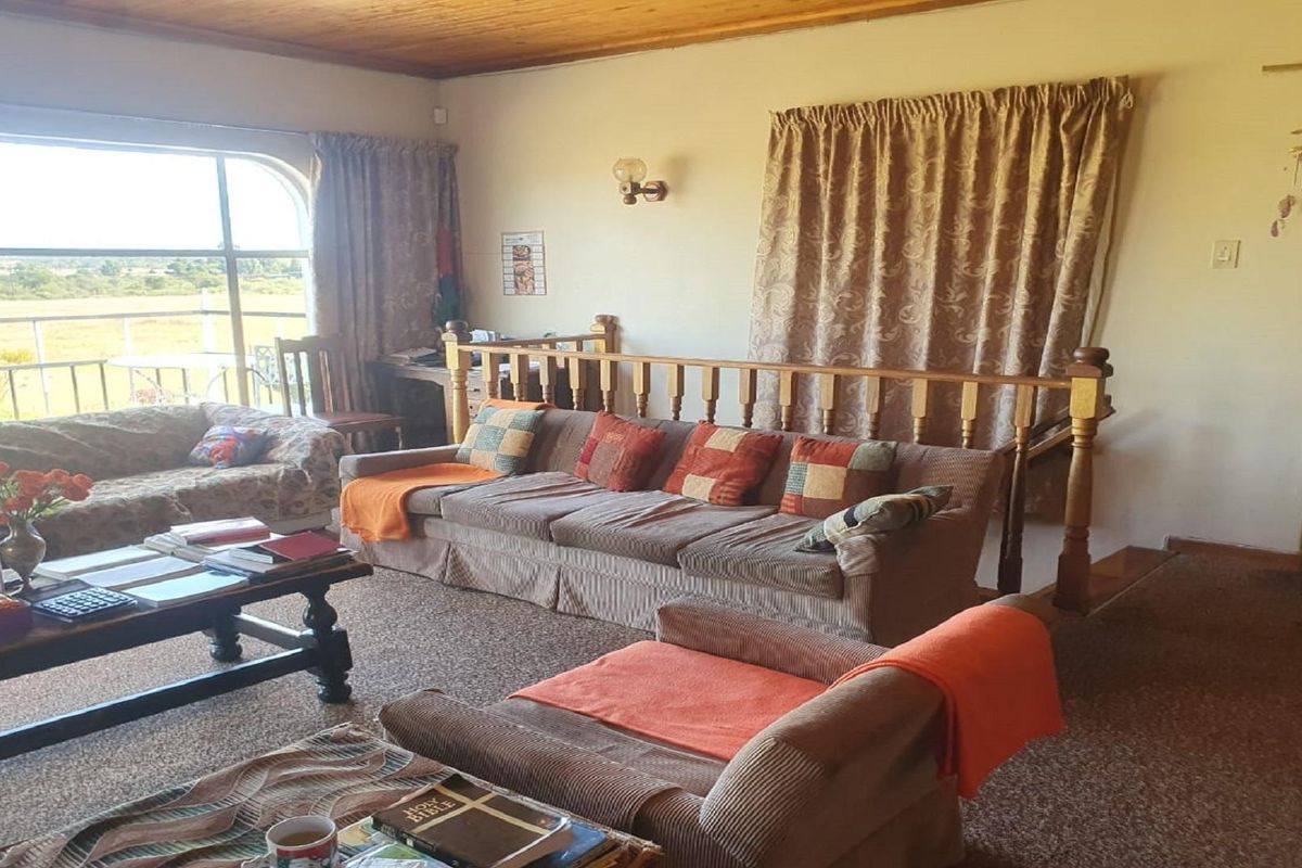 Spacious living area featuring a timber-clad ceiling, carpeted flooring, and large windows providing natural light and views of the surrounding farm landscape.