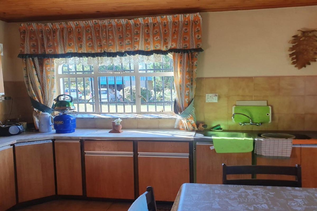 A dated kitchen featuring wooden cabinetry, a tiled backsplash, and a window overlooking the exterior grounds.