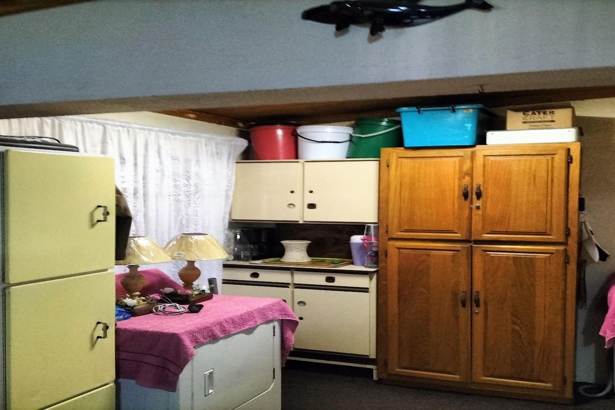 A dated kitchen area featuring built-in wooden cabinetry and storage units, showing signs of age and requiring modernization.
