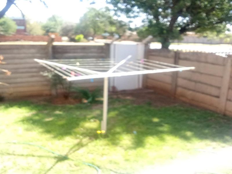 A private garden area featuring a precast concrete boundary wall and a fixed rotary clothesline.