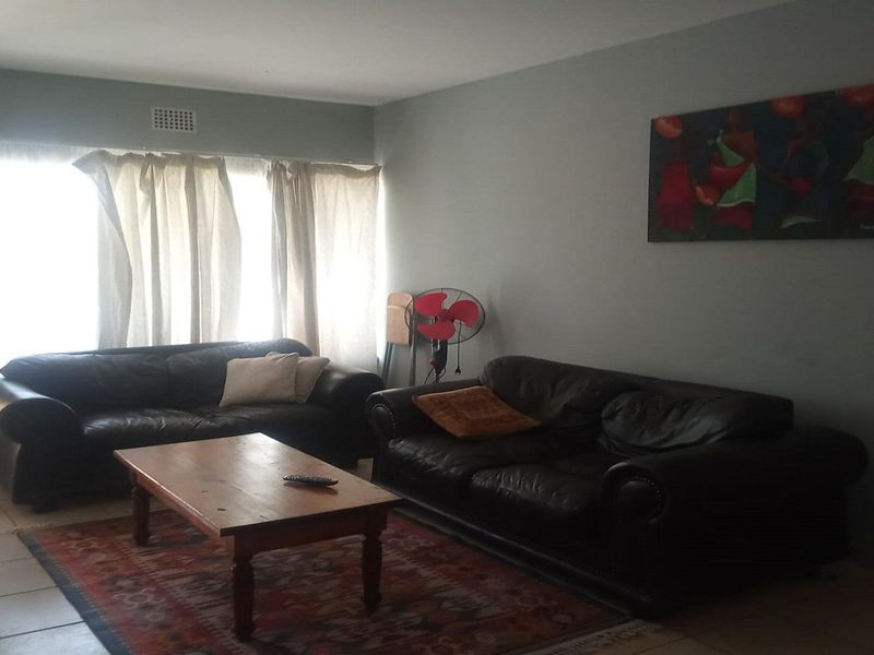 A living room area featuring tiled flooring and natural light from a large window.